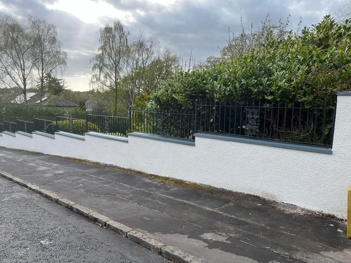 Completed white render on a boundary wall with railings by DL Plastering and Roofing